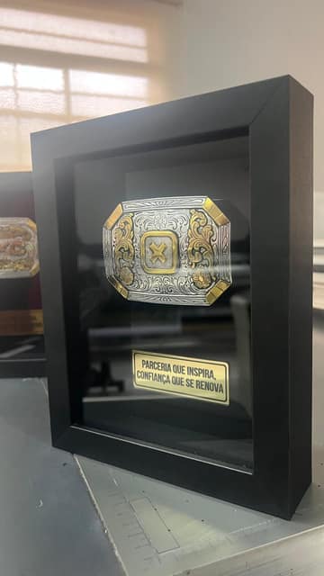 Quadro preto com fivela em relevo e placa dourada gravada, produzido para a TXC