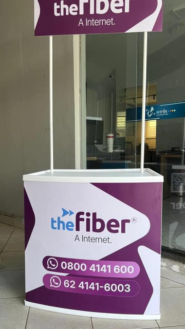 Balcão de ponto de venda da The Fiber em roxo e branco, com testeira suspensa por hastes