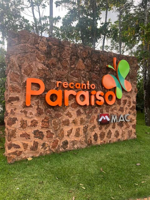 Letra caixa em acrílico laranja da marca Recanto Paraíso aplicada sobre muro de pedra