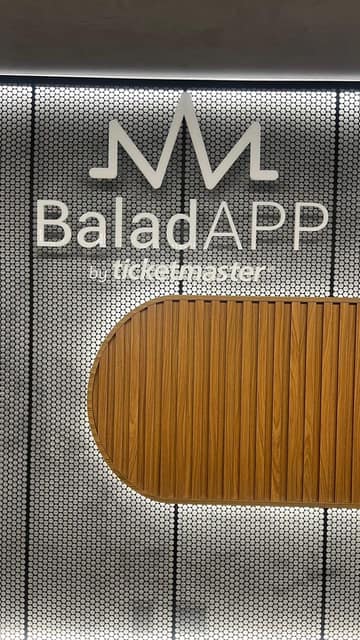 Letreiro do BaladAPP by Ticketmaster em acrílico branco sobre painel metálico perfurado