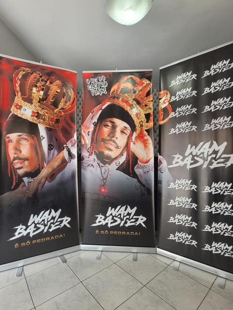 Dois roll ups e um painel de fundo do artista Wam Baster, montados lado a lado