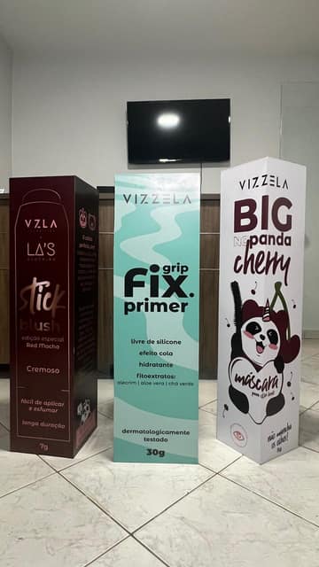 Três totens da Vizzela reproduzindo embalagens de cosmético em escala ampliada